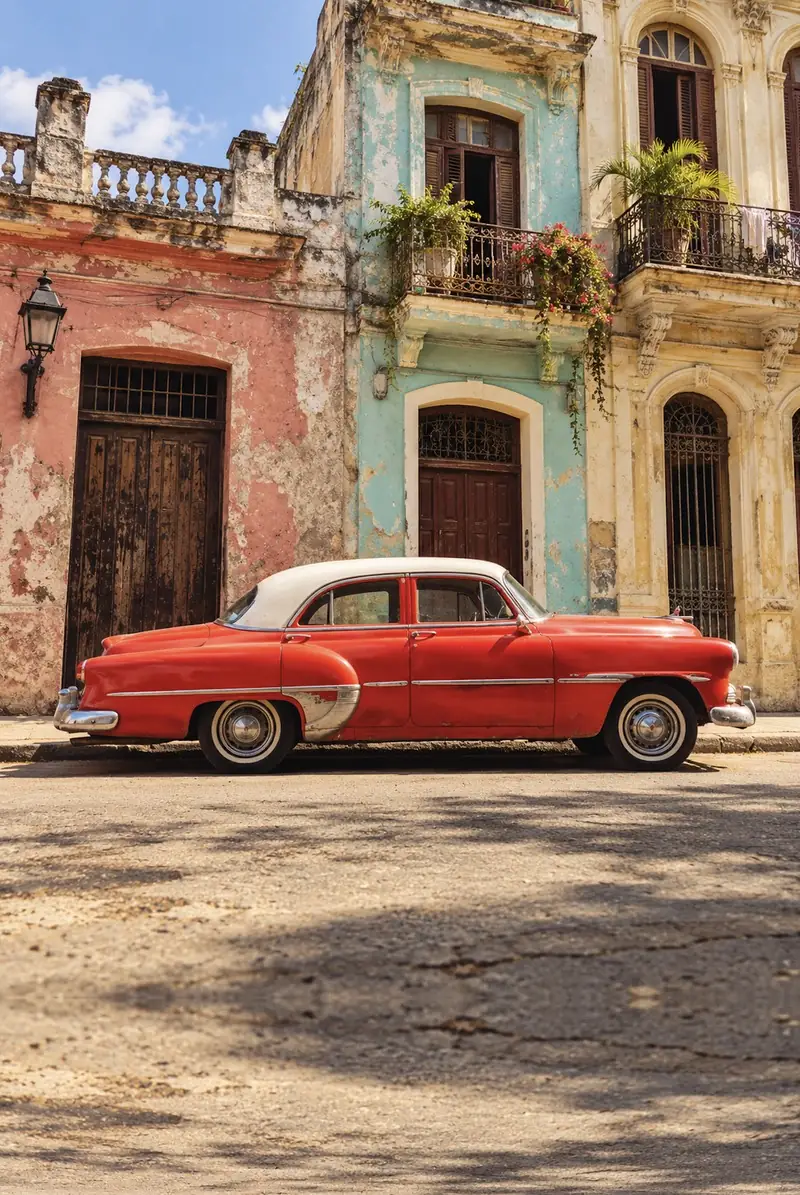 Rode oldtimer voor kleurrijke gevels in Havana, Cuba